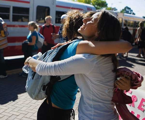 Marisa Crockett, right, hugs Scarlett Widgeon near the Yale shuttle stop Tuesday. Crockett, who gave out free hugs, is touring the country in her bio-diesel-powered car to raise awareness about global recycling.