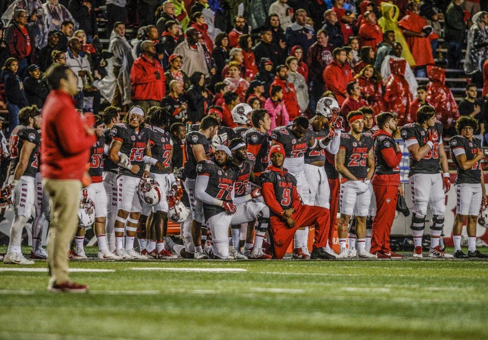 A few Lobo football players take a knee during the national anthem held during the abbreviated half-time at the Lobo vs. U.S. Air Force Academy at Dreamstyle Stadium, Saturday, Sept. 29, 2017.  Weather-induced game delays postponed the national anthem until halftime during Saturday night's match-up.