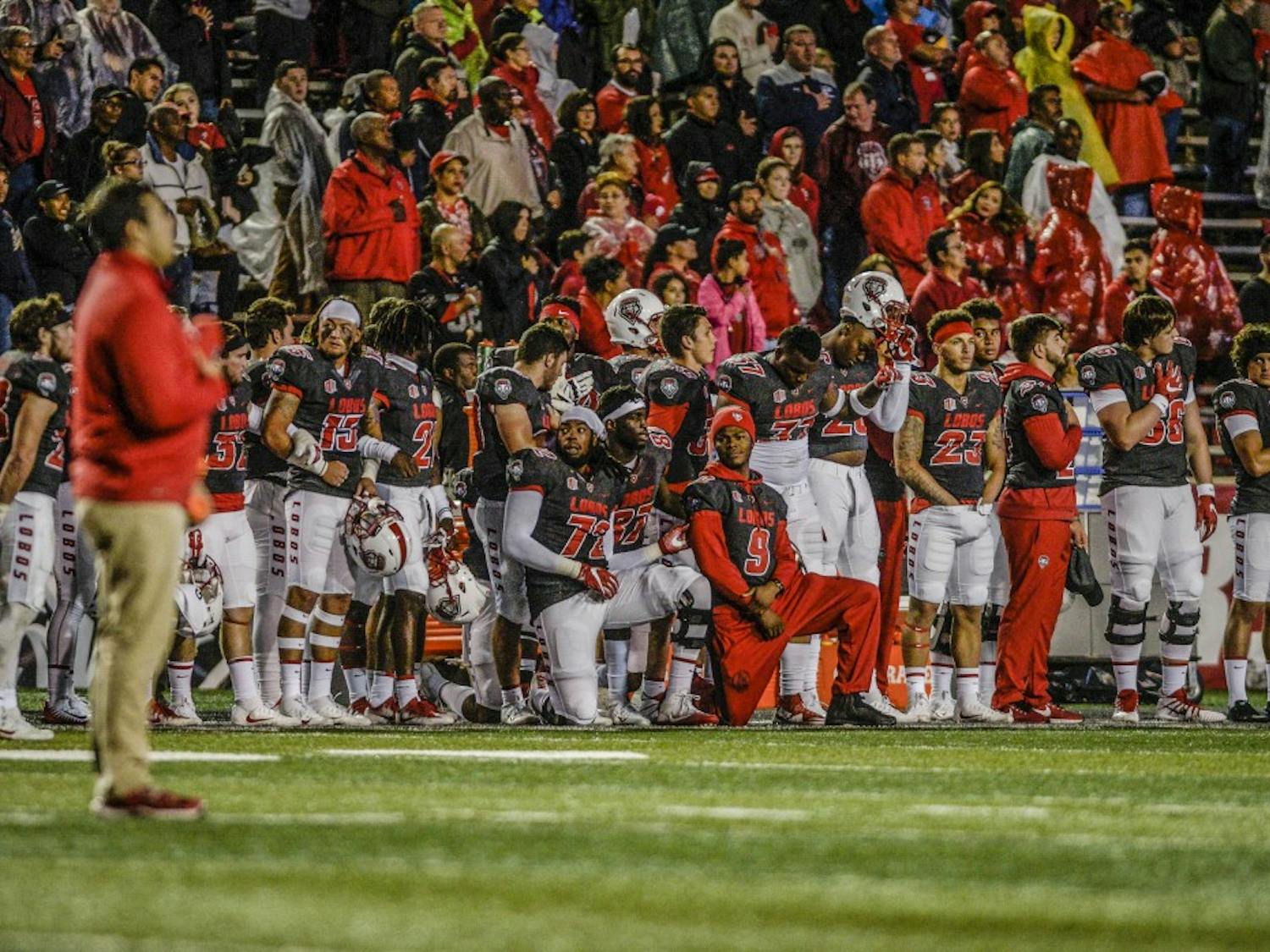 A few Lobo football players take a knee during the national anthem held during the abbreviated half-time at the Lobo vs. U.S. Air Force Academy at Dreamstyle Stadium, Saturday, Sept. 29, 2017.  Weather-induced game delays postponed the national anthem until halftime during Saturday night's match-up.