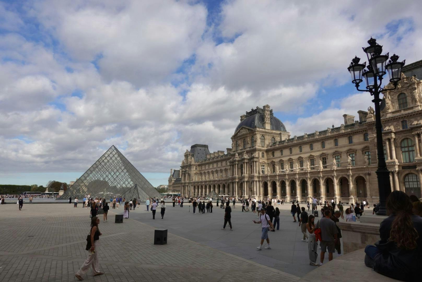 Tourists walk around the courtyard outside the Louvre. Photo by Ayla Peden.