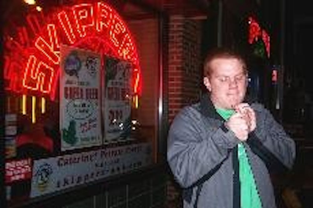 Junior Tommy Harnden must light a cigarette in front of Skippers Bar since the establishment of the law prohibitng smoking indoors.