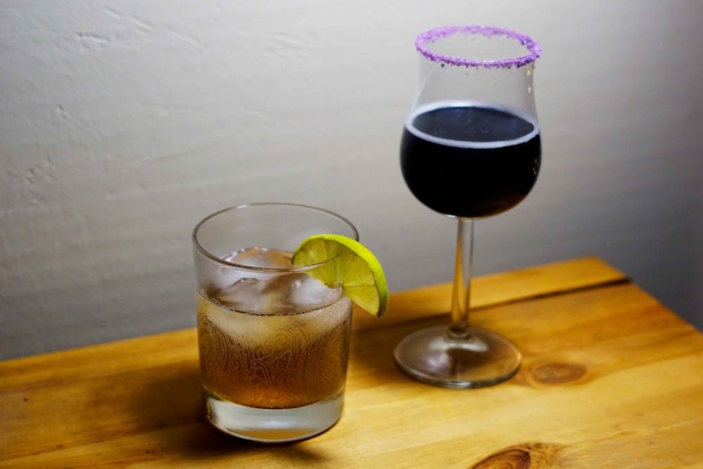 A spicy Dark 'n' Stormy served in a lowball (left) and a festive Purple People Eater in a flared glass rimmed with purple sugar.