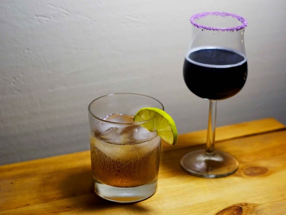 A spicy Dark 'n' Stormy served in a lowball (left) and a festive Purple People Eater in a flared glass rimmed with purple sugar.