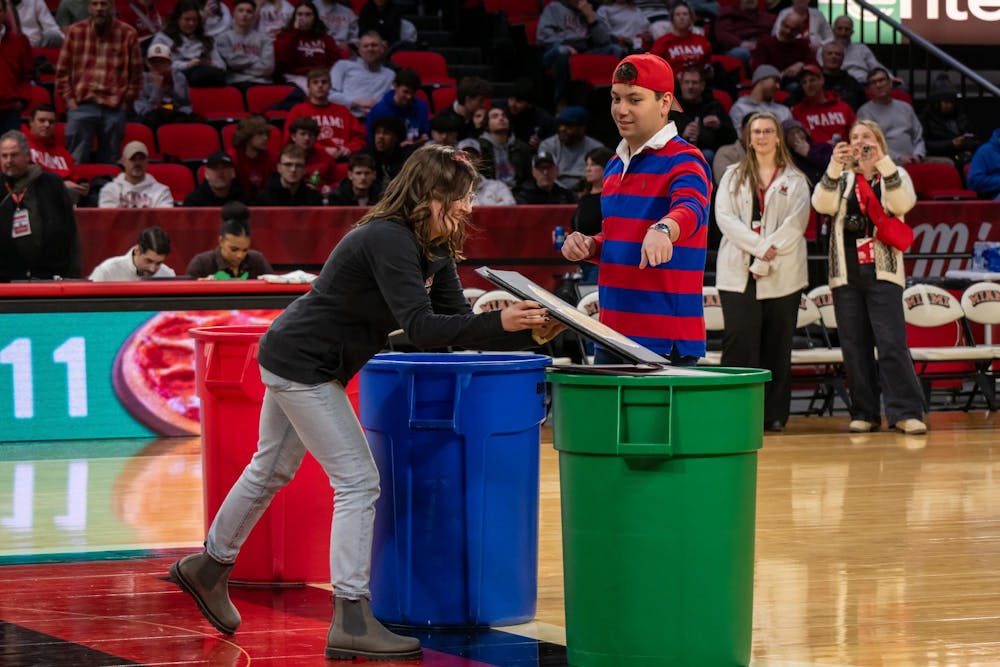 Student Body President Daniel Martin sorts waste into a recycling bin during halftime at the "Recycling with the RedHawks" game.