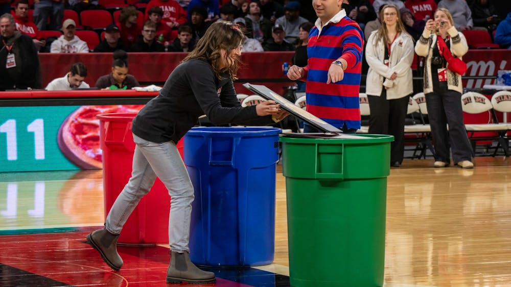 Student Body President Daniel Martin sorts waste into a recycling bin during halftime at the "Recycling with the RedHawks" game.