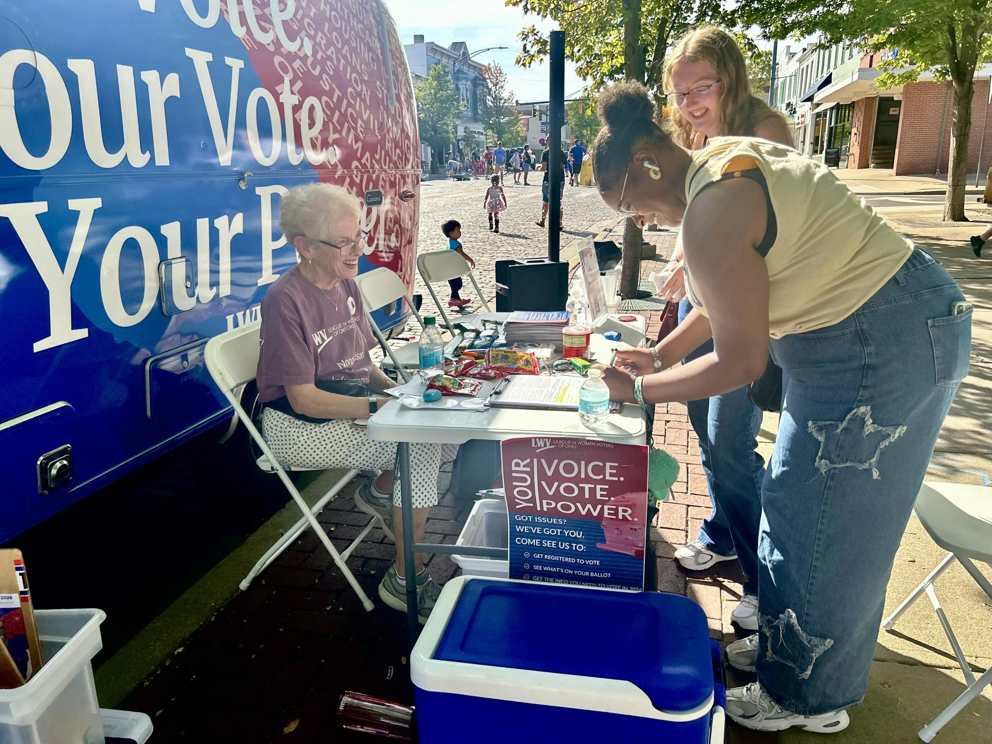 First-years Saliah Curtiss and Aubrey White stop at the League of Women Voters booth and trailer to register to vote.