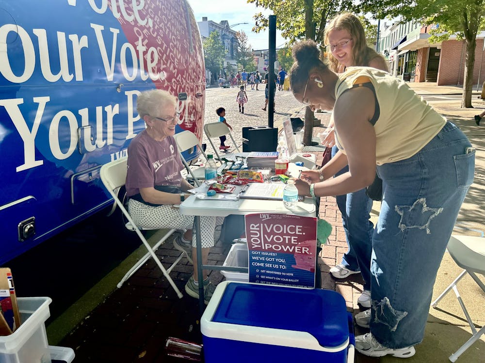 First-years Saliah Curtiss and Aubrey White stop at the League of Women Voters booth and trailer to register to vote.