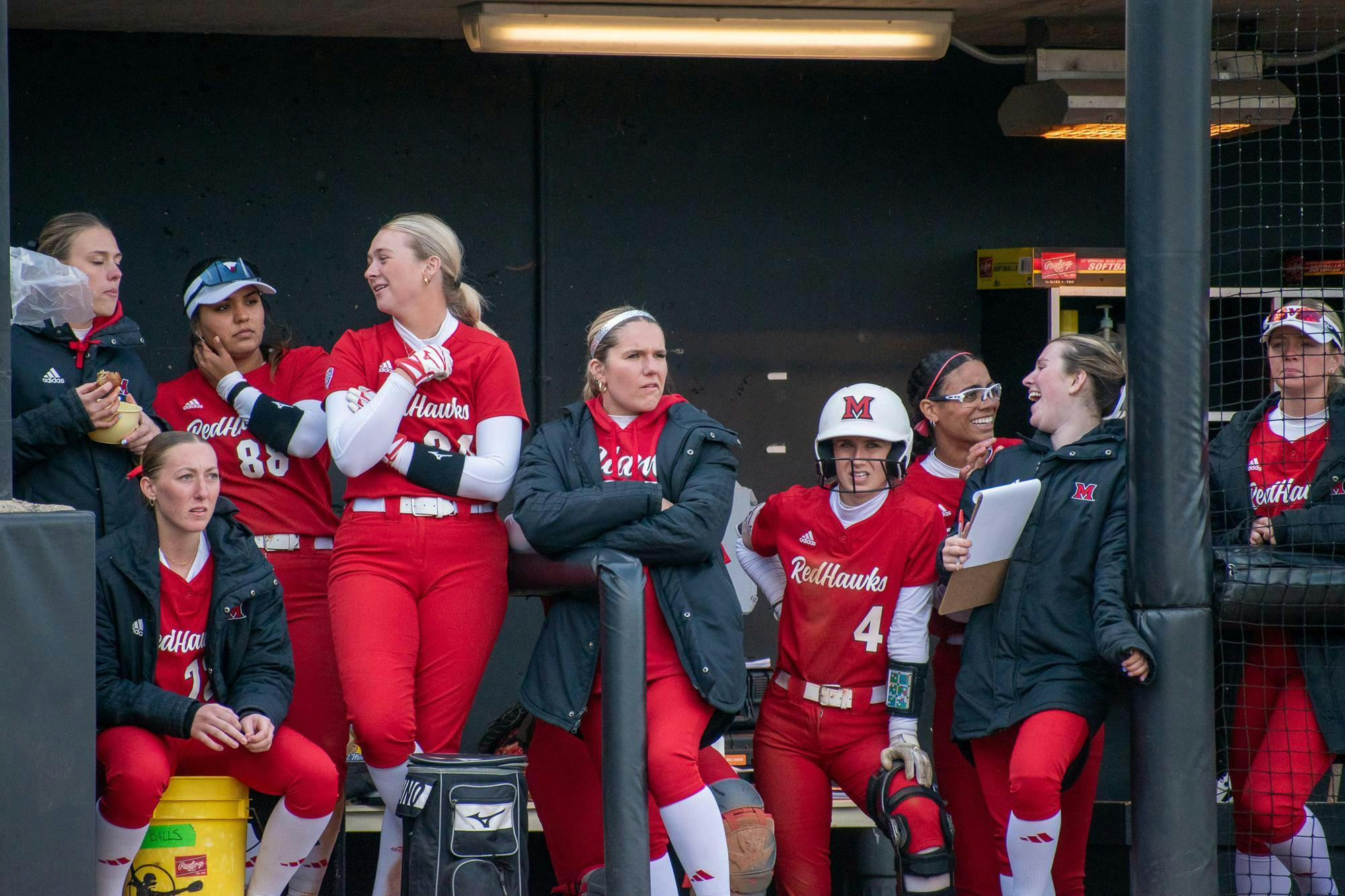 The 2024-25 softball team stands in the dugout during a game against Northern Illinois University. 