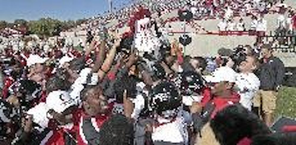 Cincinnati crowds around the Victory Bell after its 47-10 victory over Miami Saturday at Yager Stadium, capturing the trophy for the second straight year.  --Jeff Creech/The Miami Student