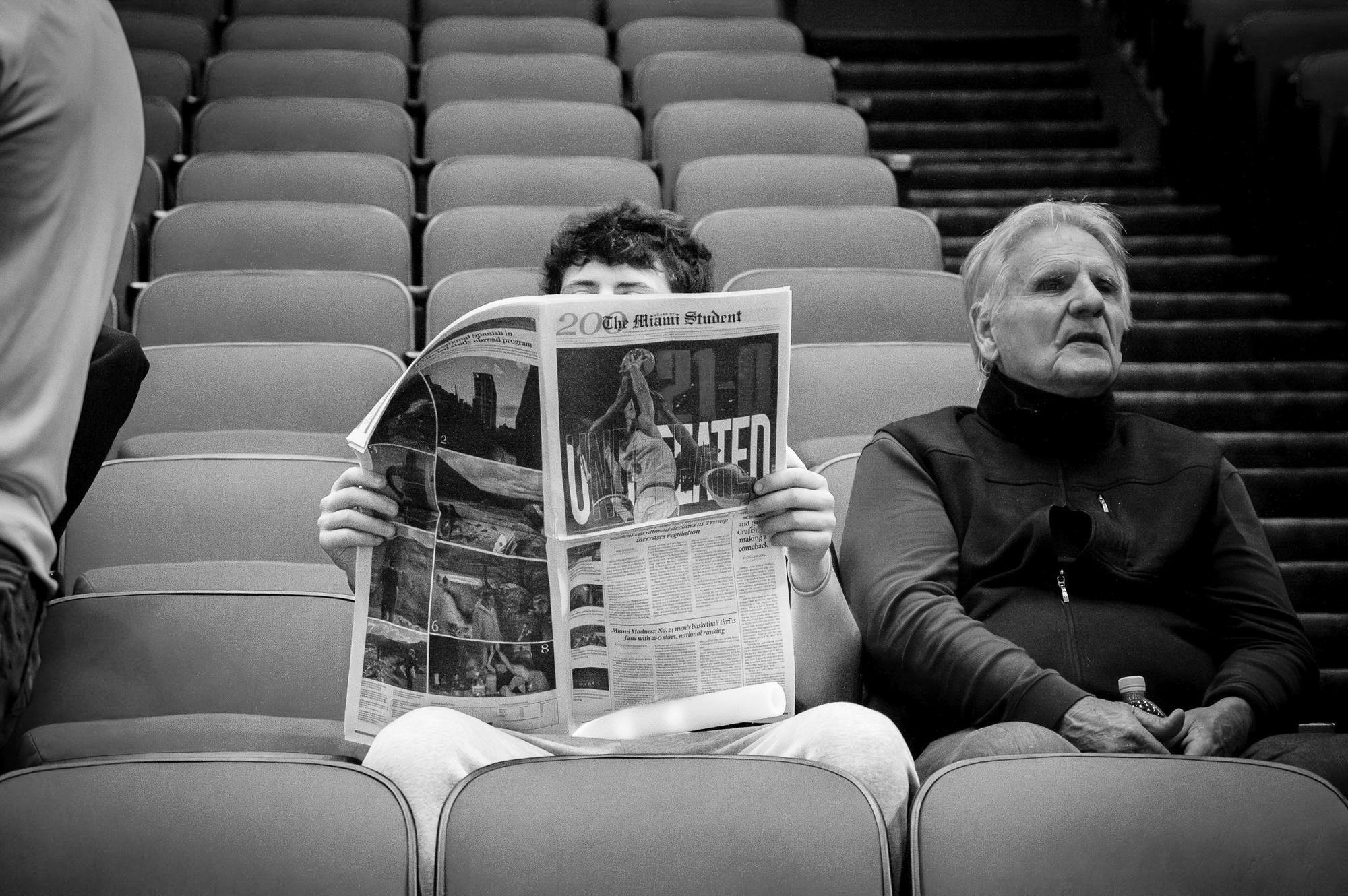 Student reads The Miami Student newspaper after a basketball game at Millett Hall.
