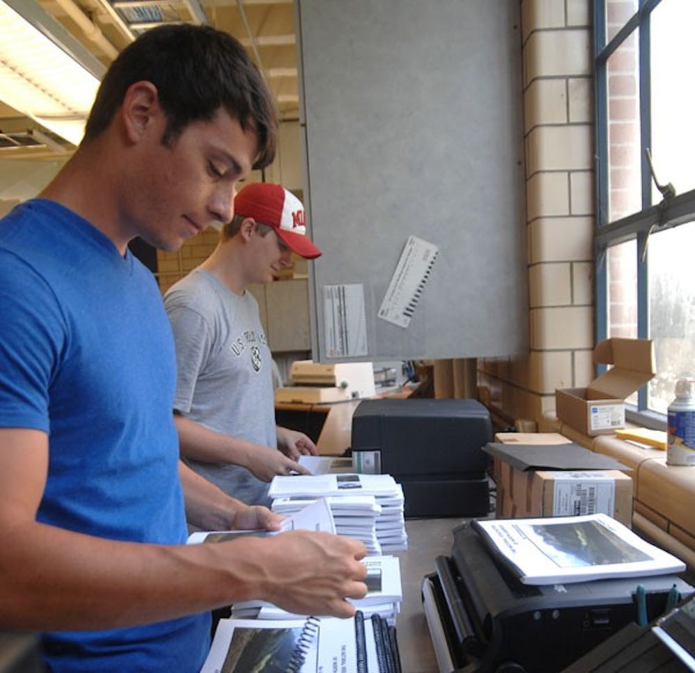Senior employees Alex Myer and Andrew Haberman bind books at the Miami University Print Center. 