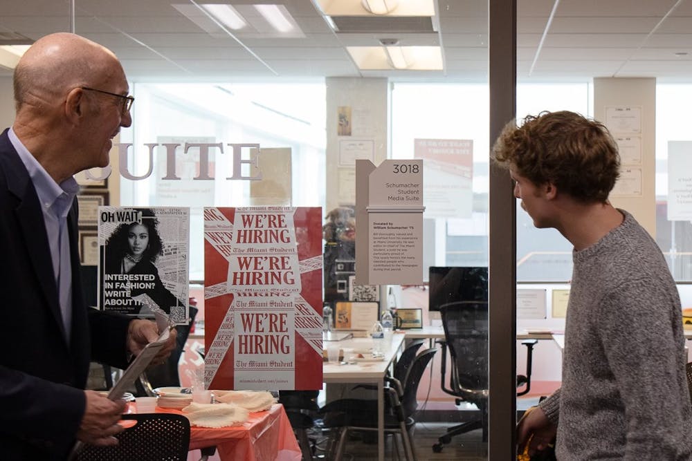 Editor-in-Chief Kasey Turman (right) reads the plaque dedicated to William Schumacher (left) after the media suite sign unveiling Oct. 4.