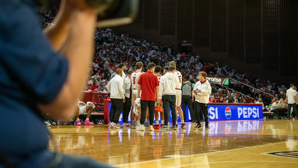 The Miami University RedHawks men's basketball team huddles in game against Ohio University.