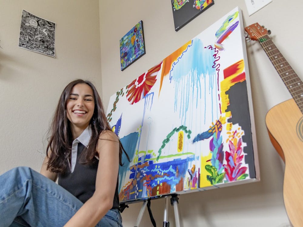 Student artist Sophia Thompson turned to painting for comfort during the pandemic. Behind her is an unfinished piece.