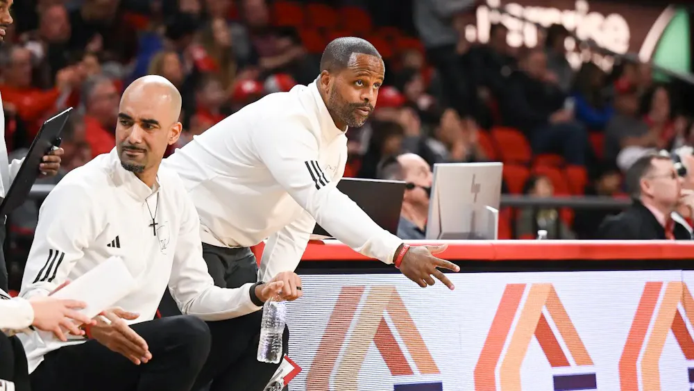 Assistant head coach Carl Richburg directs players from sideline of a Miami University RedHawks basketball game.