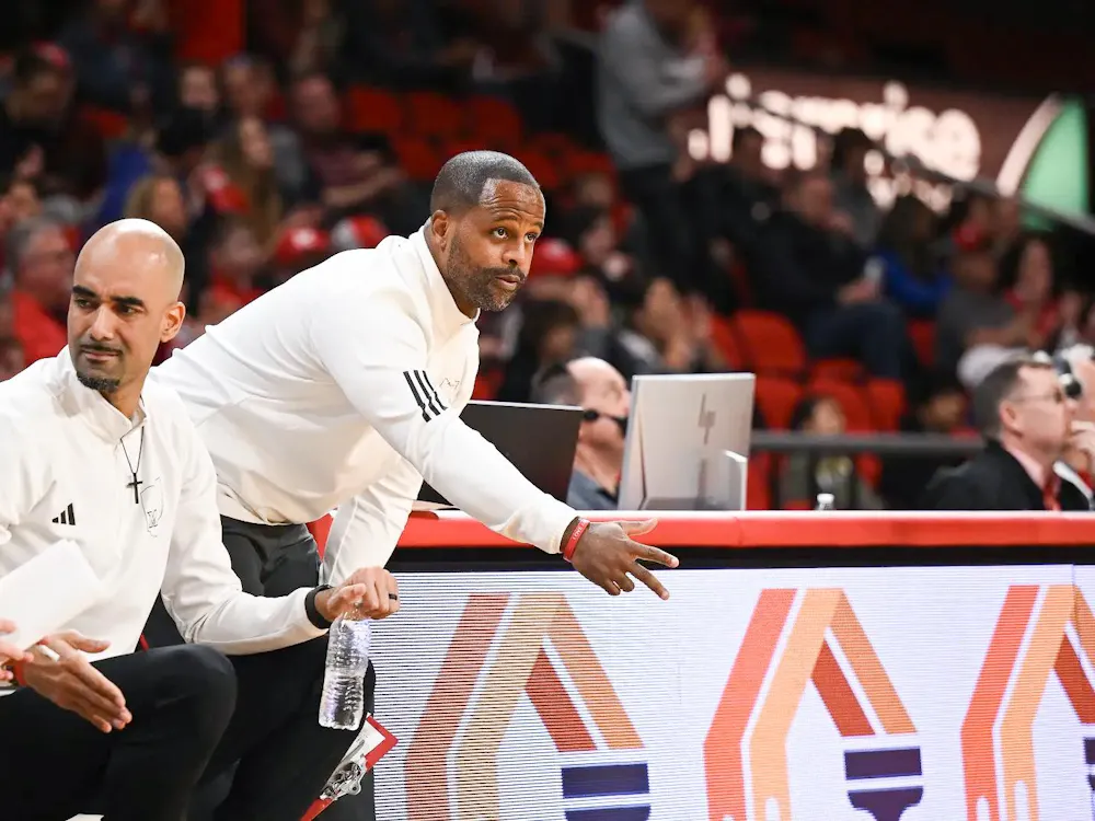 Assistant head coach Carl Richburg directs players from sideline of a Miami University RedHawks basketball game.