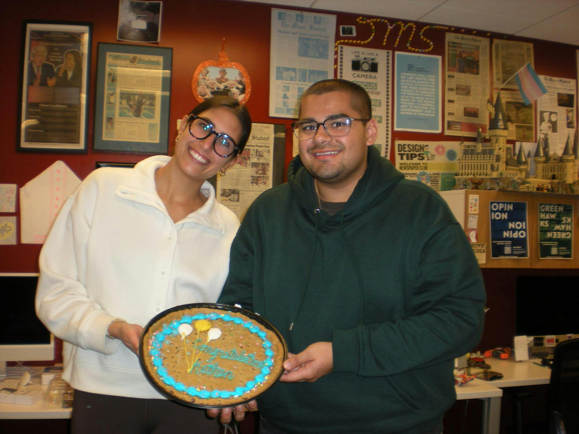 Olivia Patel (left) and Kethan Babu (right) hold a cake celebrating Kethan reaching 200 bylines in the newsroom on Nov. 5, 2025.