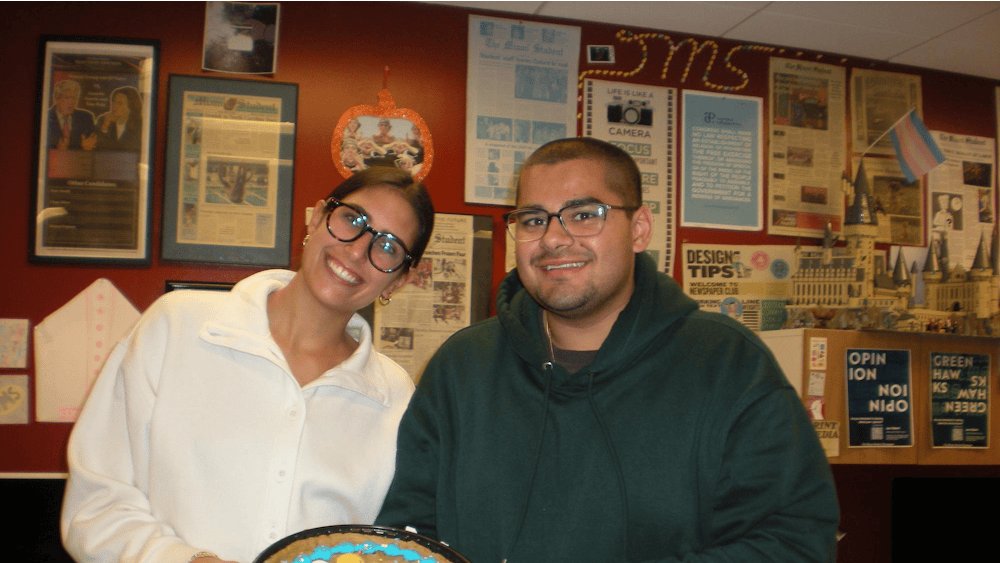 Olivia Patel (left) and Kethan Babu (right) hold a cake celebrating Kethan reaching 200 bylines in the newsroom on Nov. 5, 2025.