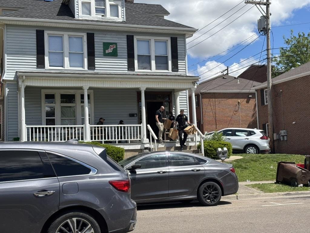 Officers remove several brown paper bags from the house.