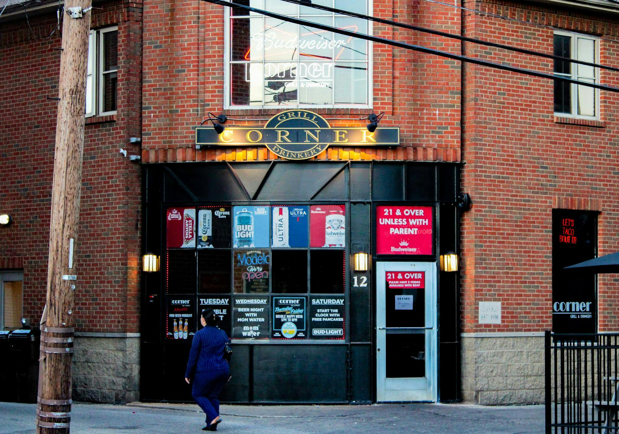 A woman walks in front of Corner grill and drinkery in Uptown Oxford.