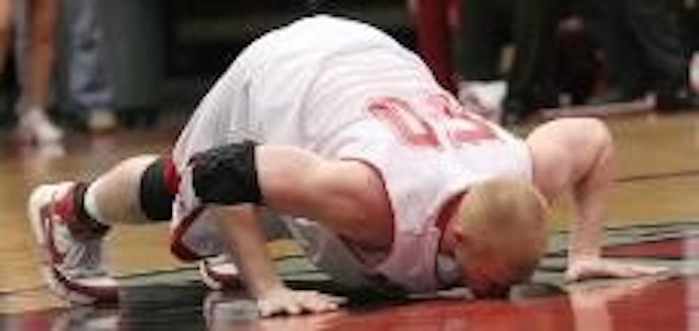 In an emotional farewell, senior forward Tim Pollitz kisses center court Sunday at Millett Hall before checking out for the last time in his final regular season game at Miami.