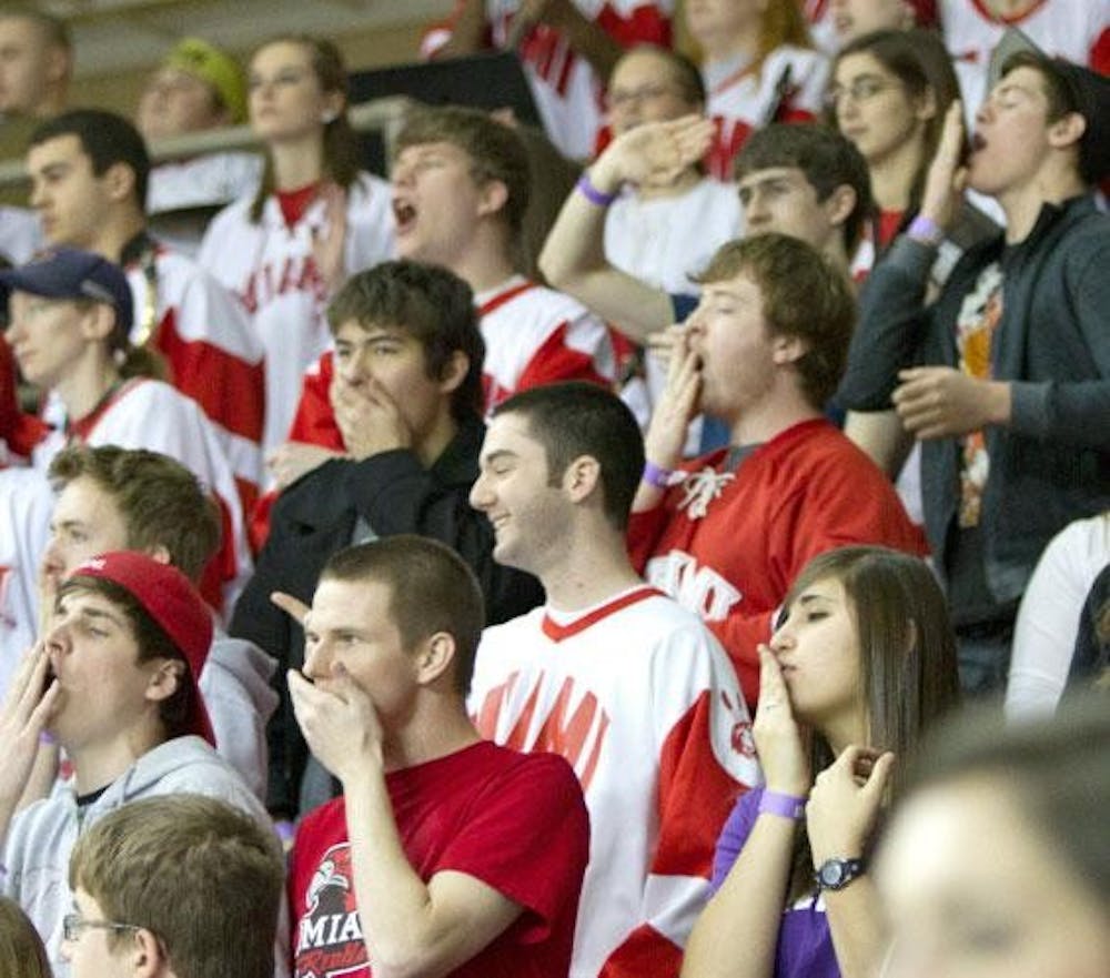 Students cover their mouths as they “whoop” during the Miami hockey game Friday night at Goggin Ice Center.