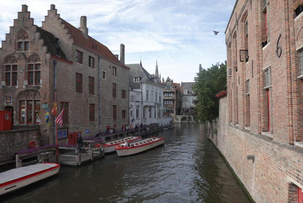The canals of Bruges with people waiting to get on tour boats.