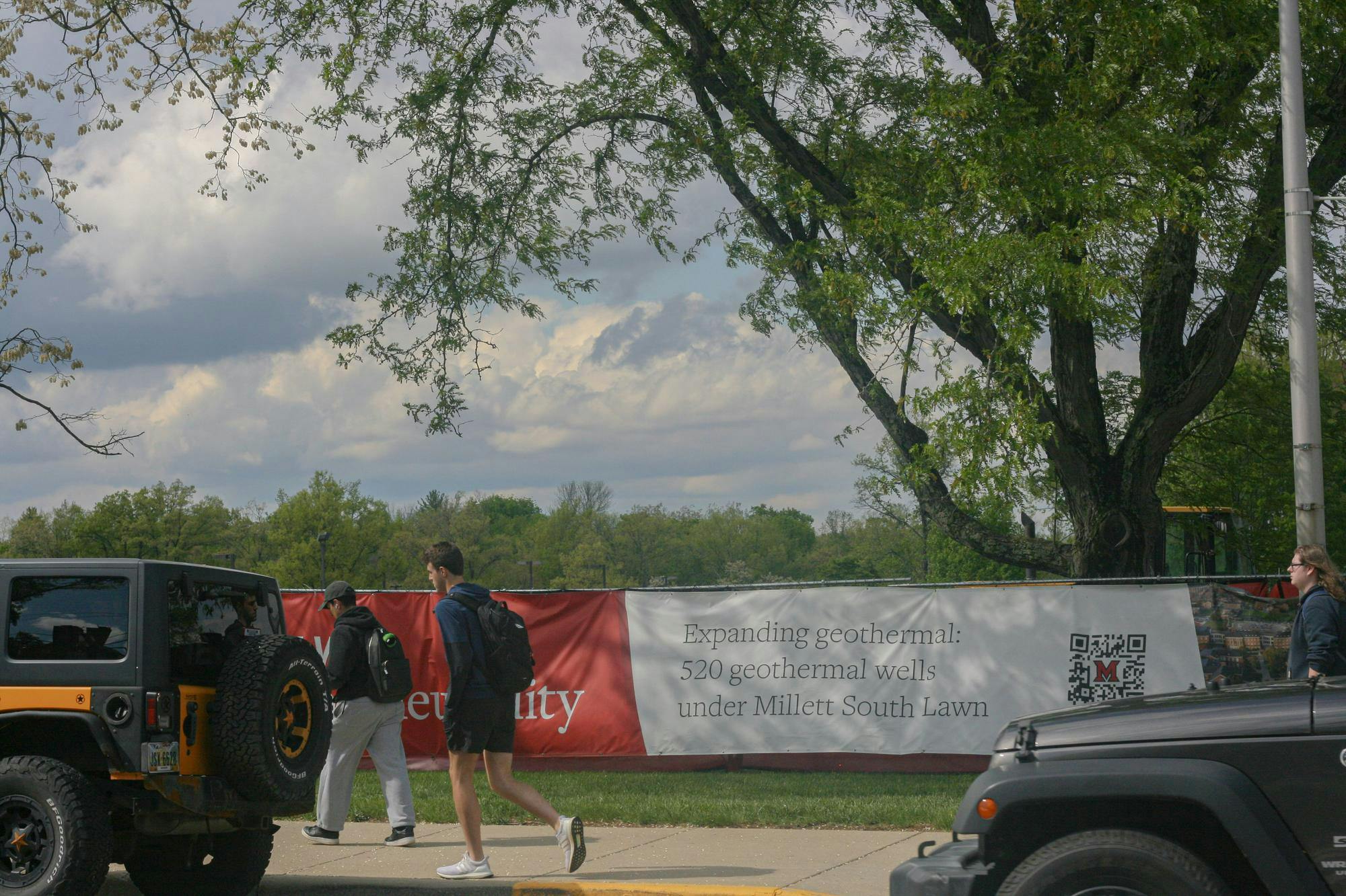 Student walks past construction site of new north campus Geothermal outside Millet Hall.