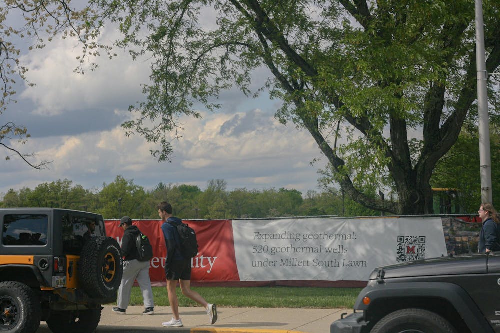 Student walks past construction site of new north campus Geothermal outside Millet Hall.