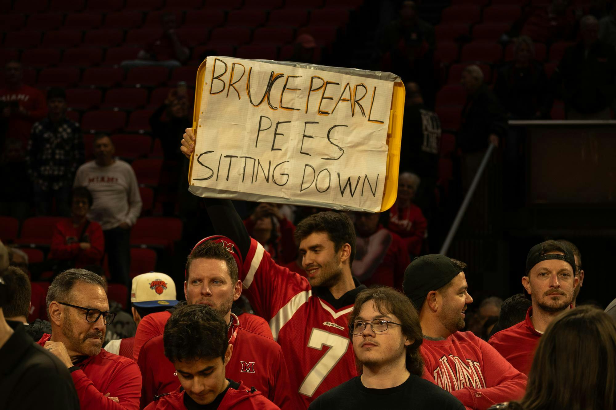 Fan stands on court holding a sign that reads ‘Bruce Pearl pees sitting down' after the Miami University RedHawks defeated the University of Toledo Rockets 74-72