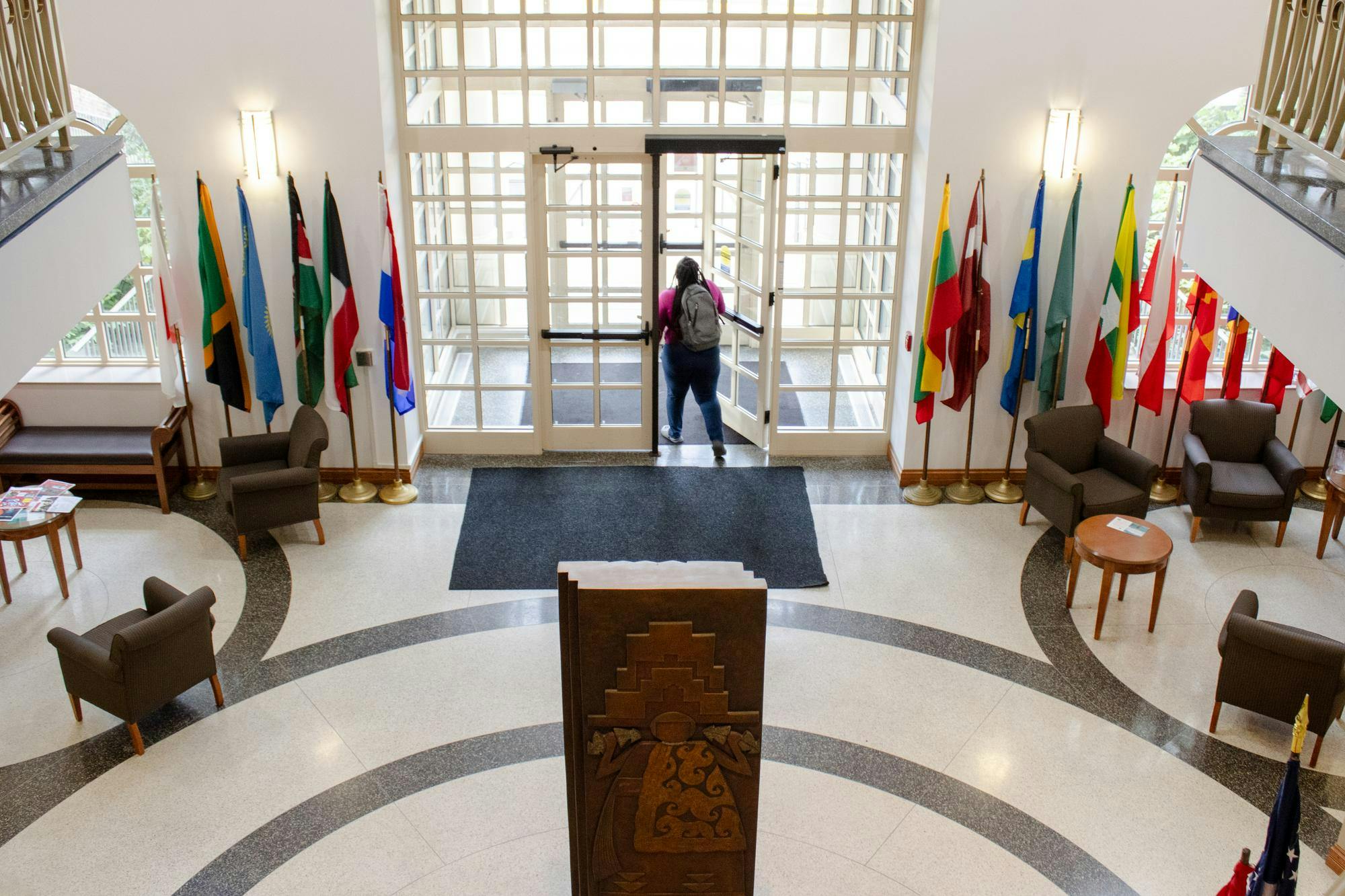 Student walking out of Macmillan Hall, home of the International Student Center.