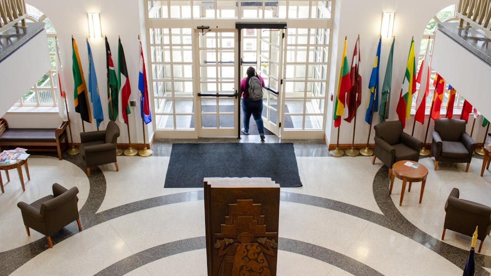 Student walking out of Macmillan Hall, home of the International Student Center.