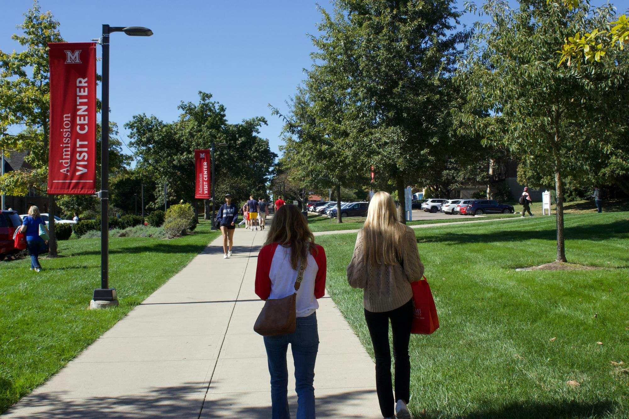 People walk with Miami University tour bags past the Shriver Center. 