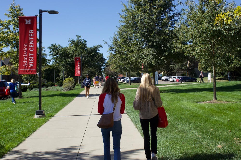 People walk with Miami University tour bags past the Shriver Center. 