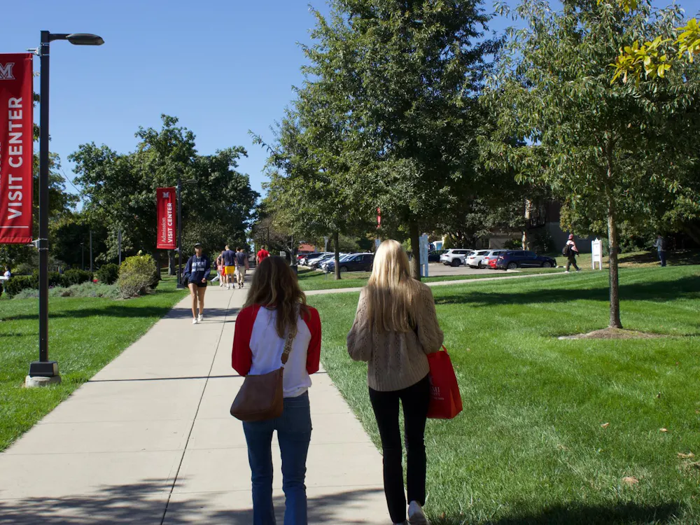 People walk with Miami University tour bags past the Shriver Center.