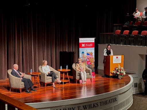 Guest speakers Gov. Mitch Daniels and Kristina Johnson sit between student-moderator Minnie Warfield. President of the JANUS Forum, Cameron Tiefenthaler, introduces the event.