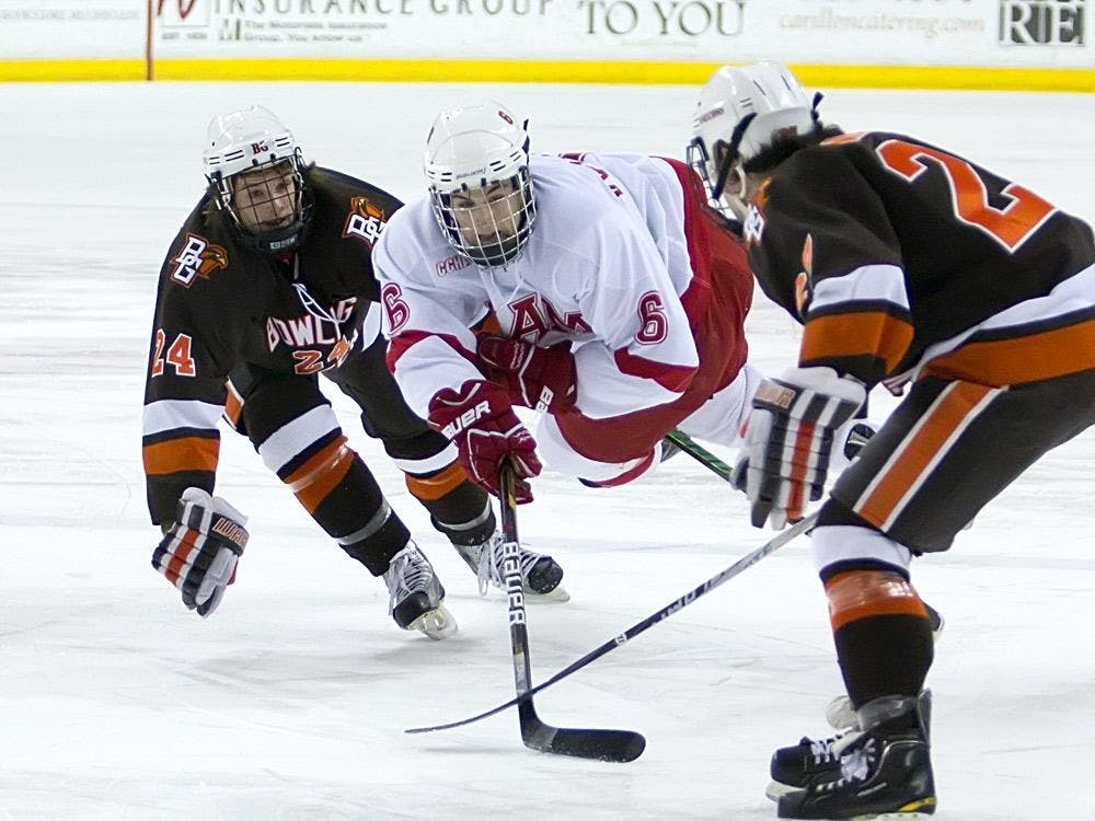 Chris Wideman soars between two Bowling Green defenders to keep control of the puck.