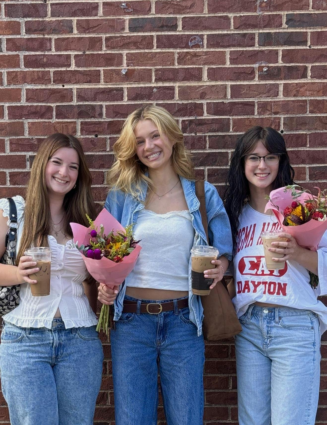 (from left to right) Hailey Boye, Kenzi Perkins and Kira Boye pose in Uptown with the flowers and coffees they bought from the weekly Oxford Farmers Market. Photo provided by Kenzi Perkins.