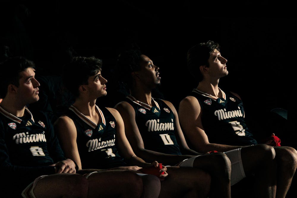 Four Miami RedHawk basketball players look towards a light illuminating from the basketball court in an in-conference game against Baldwin Wallace on Feb. 20.