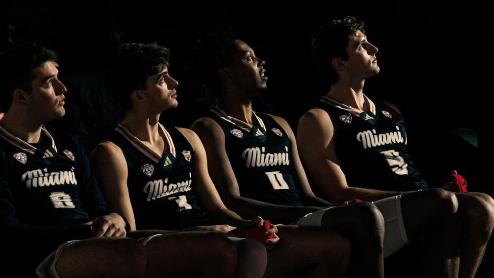 Four Miami RedHawk basketball players look towards a light illuminating from the basketball court in an in-conference game against Baldwin Wallace on Feb. 20.