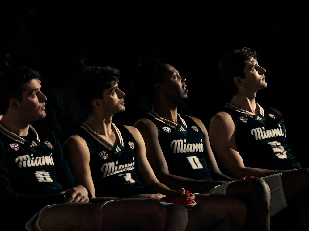 Four Miami RedHawk basketball players look towards a light illuminating from the basketball court in an in-conference game against Baldwin Wallace on Feb. 20.