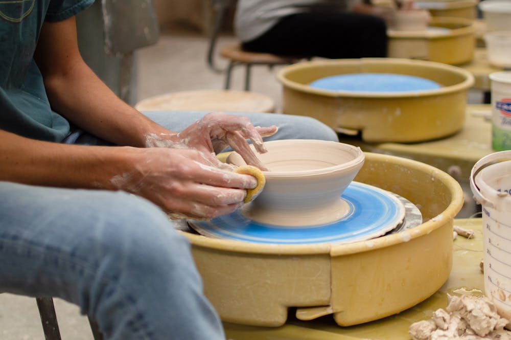 After throwing a bowl on the wheel, the ceramicist smoothes out the sides with a wet sponge.