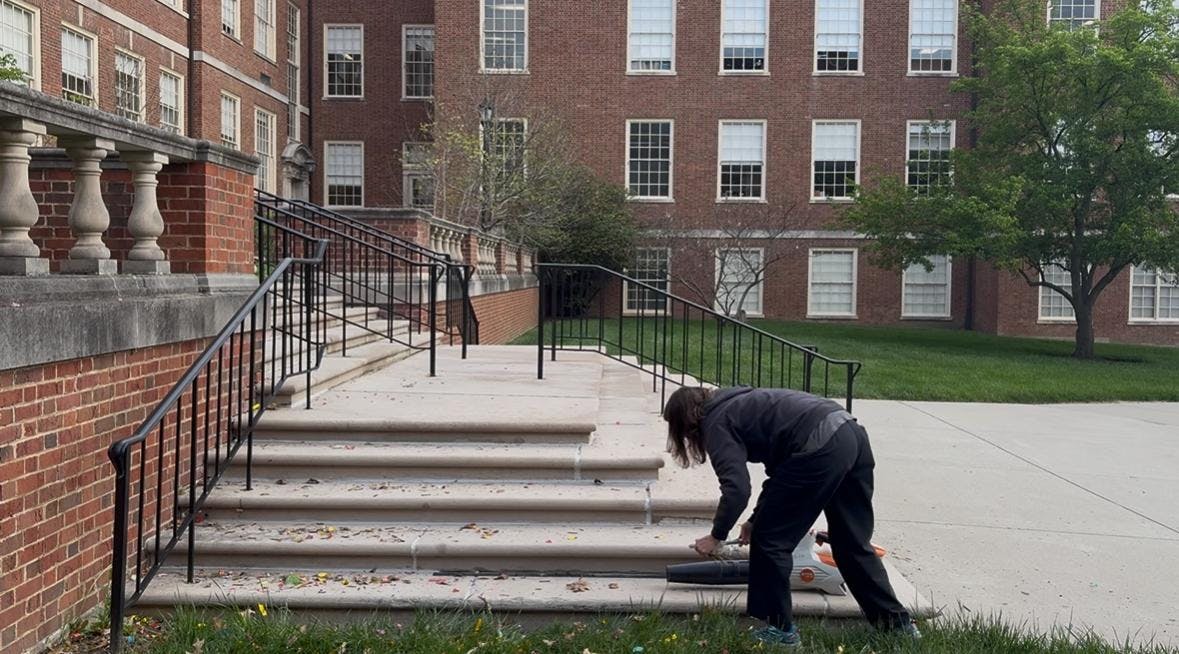 Horticulturalist Megan Croswell picks up confetti and other graduation season litter at Upham Hall. 