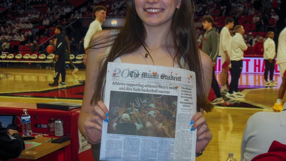 Elisa Rosenthal poses with her front-page story of the newspaper at the Miami basketball game.