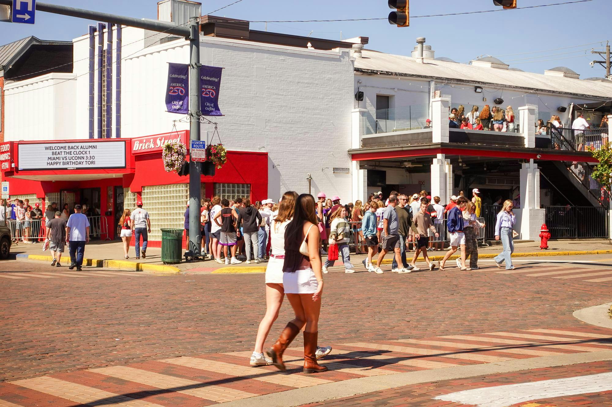 People walk across the street in front of Brick Street during Beat the Clock.