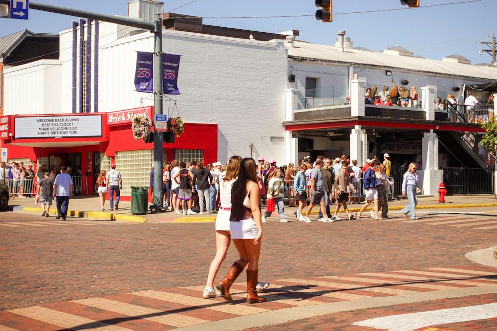 People walk across the street in front of Brick Street during Beat the Clock.