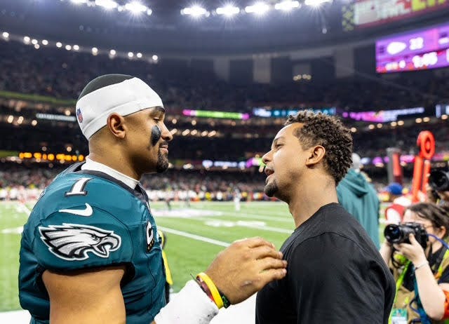 Dustin Woods (right) talks with Eagles quarterback Jalen Hurts (left) on the sidelines of the Super Bowl on Feb. 9, 2025.