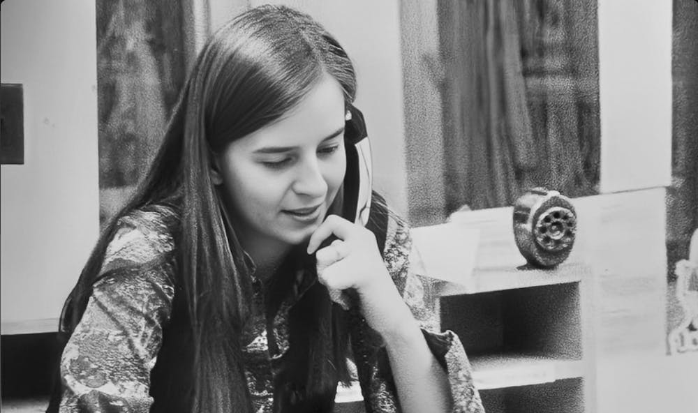 Sue MacDonald sitting on her desk in the editor's office of The Miami Student 1976-77, when the offices were on the second floor of Shriver Center.