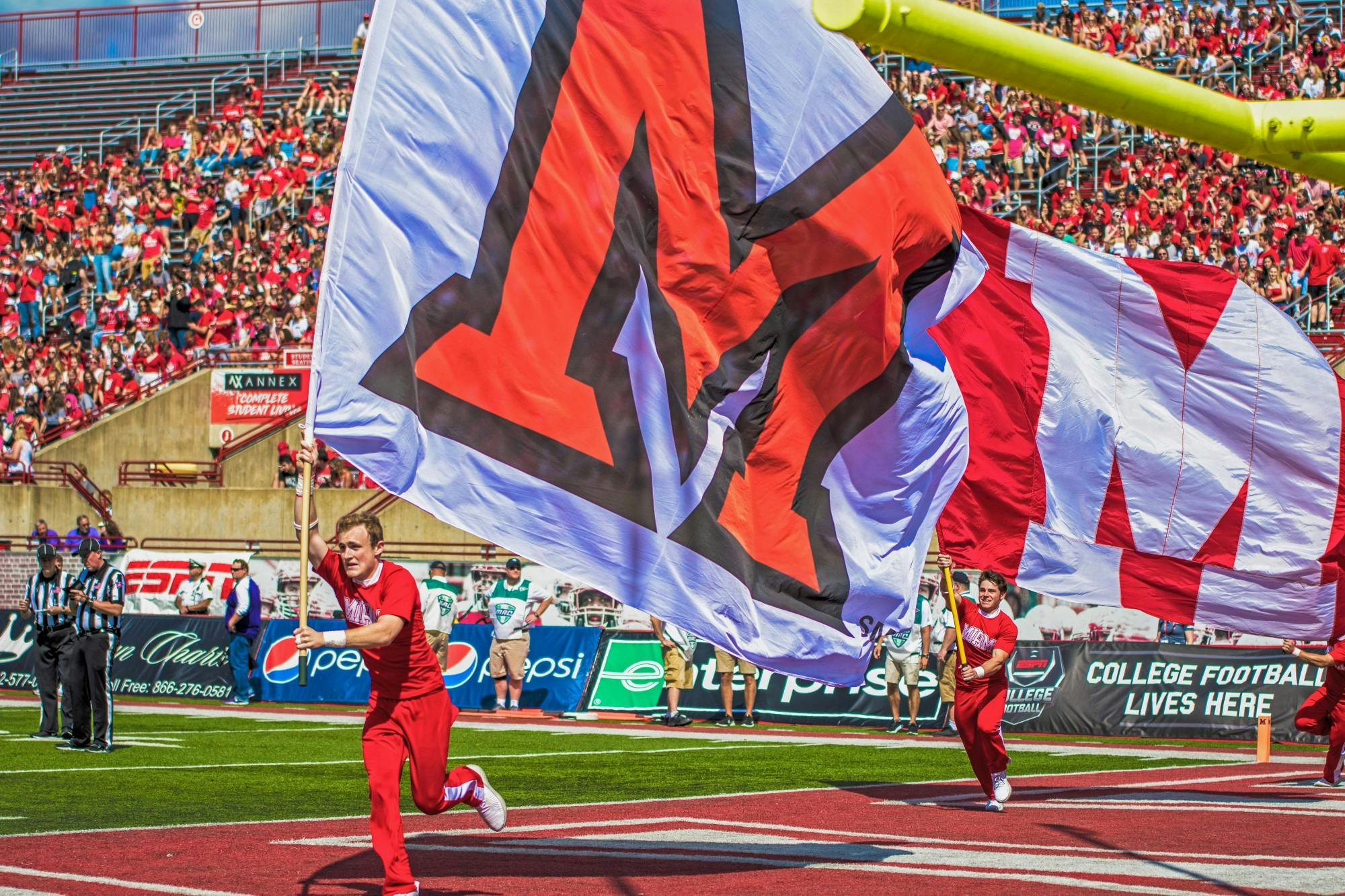 Dane Doebereiner runs across the Yager Stadium end zone with a white Miami flag. The scamper around the field is the Miami cheerleaders customary celebration when the football RedHawks score a touchdown.