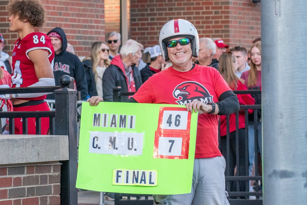 Michael Hawkins holding a sign with the final score of the Miami-Central Michigan football game earlier this season